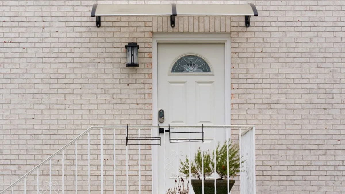 Modern metal awning over front door of a brick house with minimalist bracket design