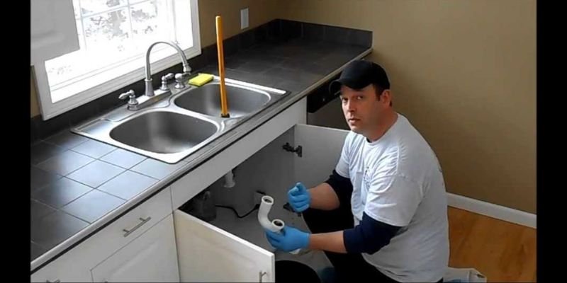 Cleaning the area under the kitchen sink after fixing a leak to prevent mold growth.
