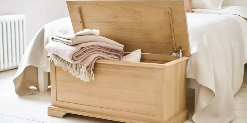 a wooden chest sitting on top of a bed in a bedroom