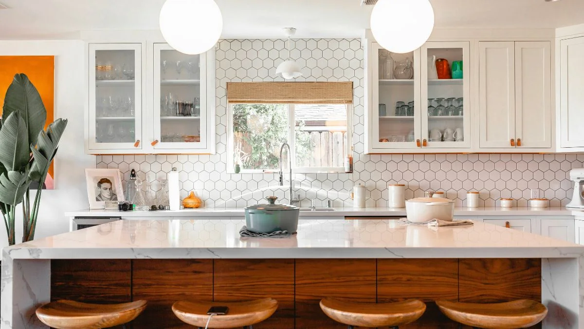 Kitchen lighting ideas with white globe pendant lights hanging over a marble island with hexagon tile backsplash