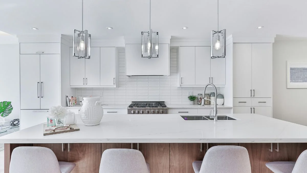 Modern glass and chrome pendant lights with Edison bulbs hanging over a white kitchen island